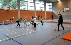 20200724_092550-1_preview_0 Beim Unihockey ging es in der Unterstufengruppe zur Sache., Draussen erwartete die älteren Teilnehmer ein Geschicklichkeitsparcours., Dort konnten sie ihre Fertigkeiten mit Schläger und Ball unter Beweis stellen., Die beiden Co-Projektleiter Ryan Hamilton und Angela Brüngger sind mit dem Ferienplausch zufrieden., Nach so viel Bewegung ist eine Znünipause angebracht.