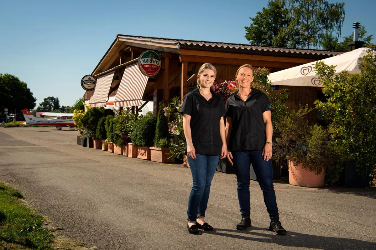 fehraltorf_24062020_restaurantimspeck_sbo_6_preview_0 Cheyenne Kessler (l.) und Sabrina Gisler kümmern sich seit Anfang Jahr um das Lokal auf dem Flugplatz., Restaurant-Gründer Christoph Kessler starb Anfang Jahr an Krebs., Die Flaggen standen deshalb auf Halbmast. Die Trauer um Chrigi Kessler war gross.