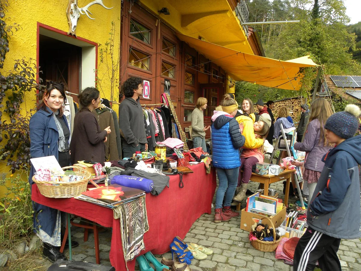 Für das Saisonende vom Schöntal-Kiosk wurde spontan ein Flohmarkt organisiert., Das Duo Luftibus erklärte dem Publikum, wohin die musikalische Reise geht., Der junge Mann in der Mitte erklärte, wie die zuvor gezeigte Fingerakrobatik vom Teatri Mobili funktioniert., Frohnatur Adi Rey ist die Seele vom Spielwerkplatz., Der Kiosk im Schöntalquartier bietet eine Auswahl an Getränken für Gross und Klein., Beim Crêpes-Stand gab es viel zu tun., «Nur noch etwas am Nuggi saugen und dann fahre ich ab», dachte sich wohl dieser kleine Rennfahrer., Früh übt sich: Dieses kleine Mädchen machte die ersten Versuche, um später als Akrobatin zum Zirkus zu gehen.