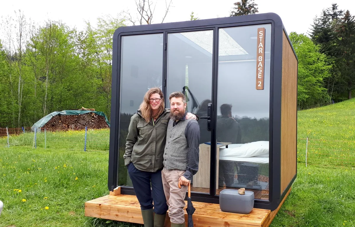 180521_starbase_1_bes_preview Die beiden Gastgeber Martina und Andreas Guyer vor der Star Base auf ihrem Bauernhof im Sternenberg., Zwei Bungalows stehen auf einer Wiese ihres Landwirtschaftsbetriebs, vorerst für eine Saison.