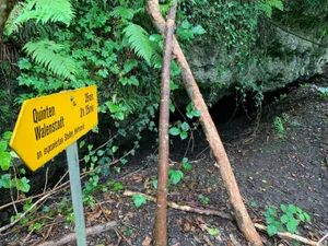 220821_wanderweg_4_cb_preview Ein schöner Wegweiser mit falschen Angaben: das Werk eines Witzbolds., Eine Höhle bietet verirrten Wanderern Unterschlupf., Ein bedrohliches Felsband wölbt sich über den Wanderweg. , Wer diese Treppe erklimmt, wird bald den Wald verlassen.
