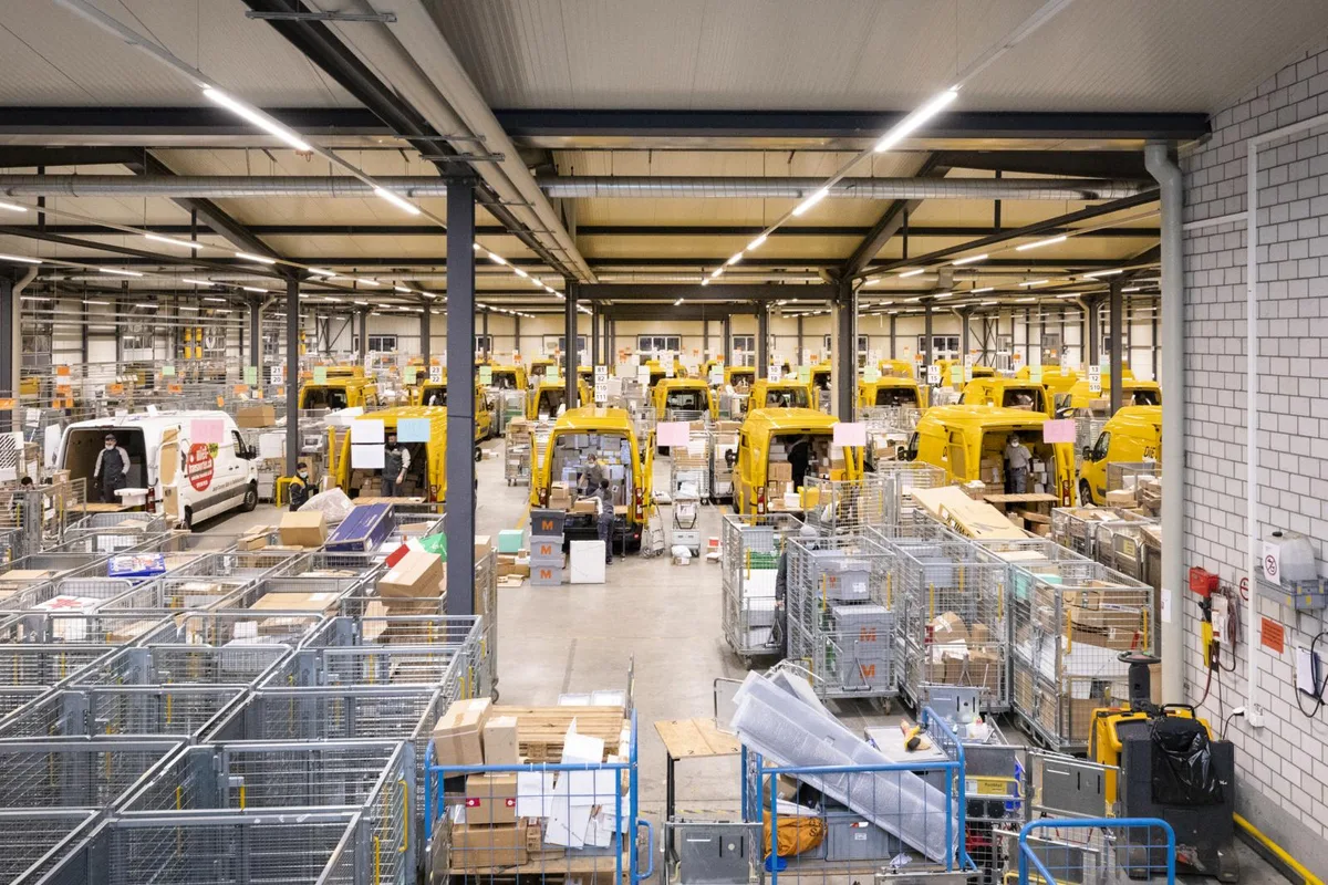 _oho6807_preview Im Logistikzentrum in Hinwil arbeiten in der Adventszeit 110 Paketbotinnen und Paketboten., Die Pakete in den vollgepackten Gitterwagen müssen erst einmal alle den Weg in den korrekten Lieferwagen finden., Das Einladen in die gelben Lieferwagen wird stets von zwei Boten erledigt.