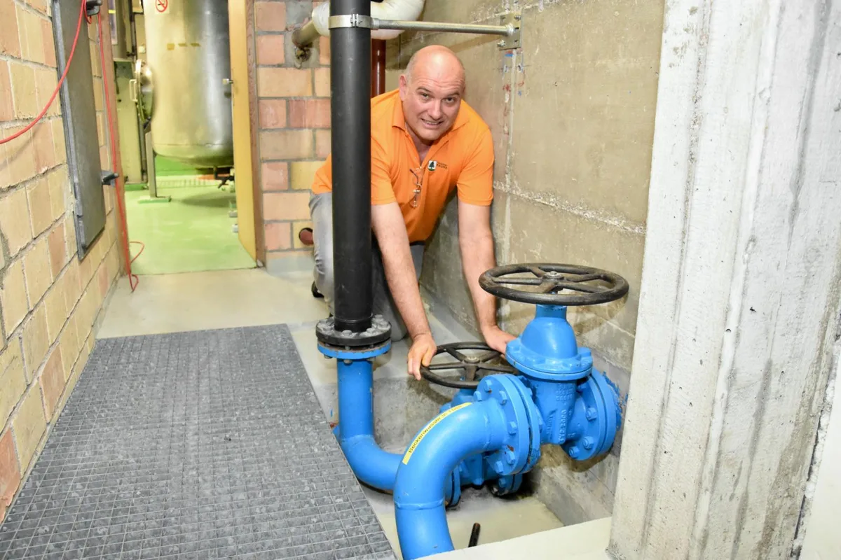 Man sieht Nardo Gramatica, der Abteilungsleiter Hallenbad, wie er an einem grossen Hahn dreht.