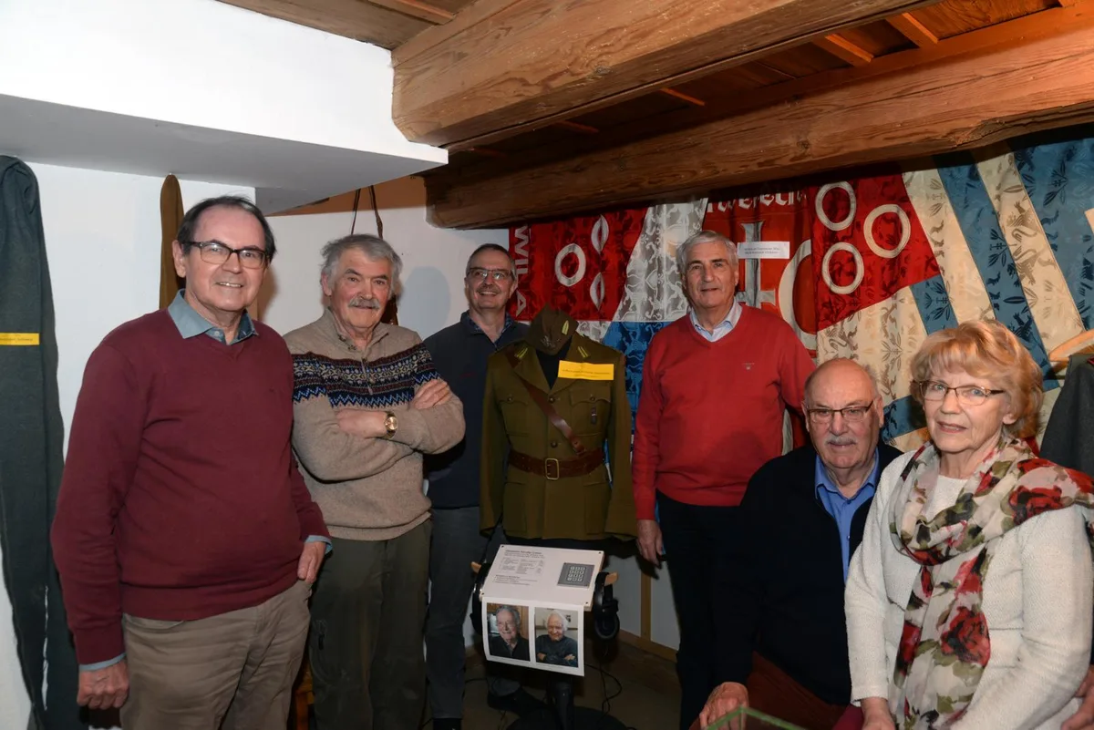 Nachfahren von polnischen Internierten besuchen die Ausstellung, die Wolfgang Wahl (dritter von links), gestaltet hat., Die Kirche von Wila war das Lieblingssujet der französischen Internierten. Drei dieser Gemälde sind im Ortsmuseum Wila zu sehen., Ein Briefwechsel zwischen der Familie Lüssi aus Wila und einem polnischen Internierten Franz Makles., Ein Nähtisch: Der Frauenverein Wila besorgte die Wäsche der Internierten. So könnte es damals ausgesehen haben., Holzschachtel, die als Souvenir von Internierten gefertigt wurde.