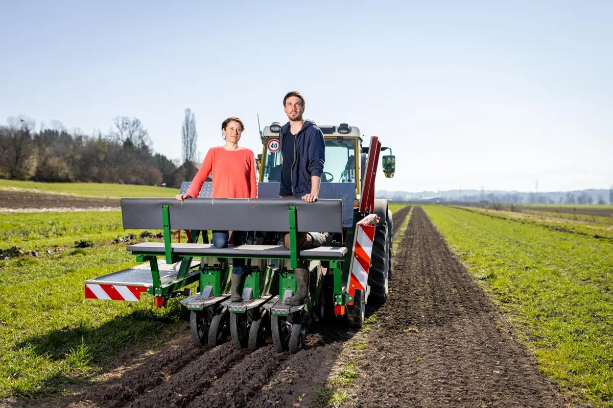 Petrissa Eckle und Matthias Hollenstein gründeten eine AG, um die weitere Forschung und Entwicklung durch Stiftungsgelder zu finanzieren. Eine Frau und ein Mann stehen nebeneinander auf dem hinteren Teil eines Traktors, der sich auf einem Acker befindet.