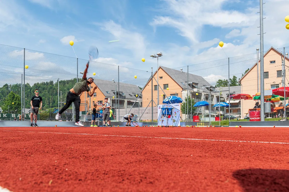 Beim Gmeiwerch Turbenthal kann auf den renovierten Plätzen wieder Tennis gespielt werden., Auch die kleinsten Talente dürfen das erneuerte Rot testen., Clubpräsident Markus Küng führte durch die offizielle Einweihung der Plätze …, … und enthülle die Sponsorentafel beim Clubhaus., Gemeinderat René Gubler zeigte sich erfreut über das gelungene Werk., Die Plätze bestehen&nbsp;jetzt aus einem Kunststoff-Ziegel-Gemisch., Für das Einweihungs-Match brauchte es natürlich eine Teamabsprache., Am Schatten verfolgten die Gäste das Können der Tennisspieler.