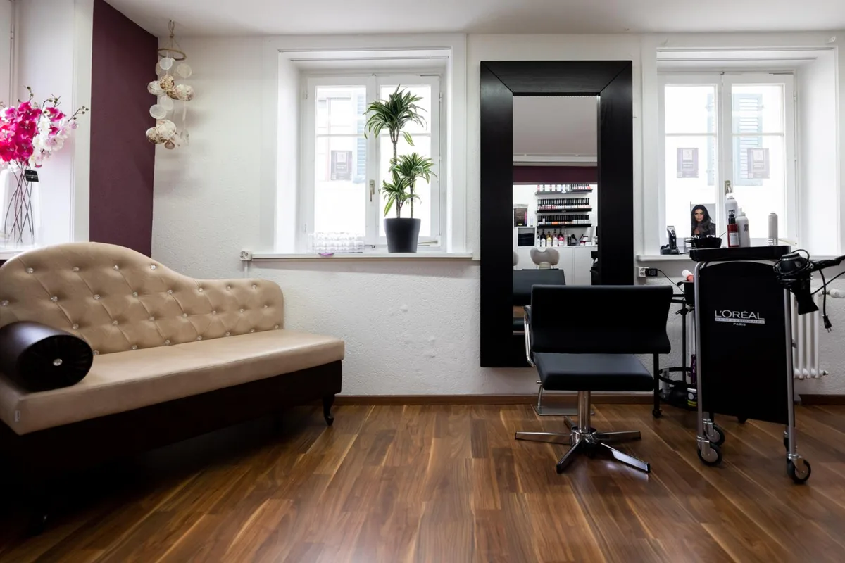 Coiffeursalon mit Sofa, Spiegel und Coiffeurstuhl. 