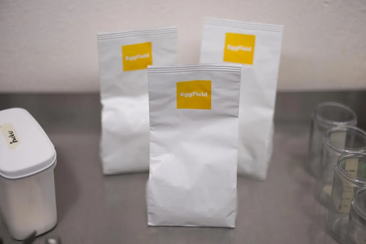 Drei weisse Tüten stehen auf einem Tisch. 