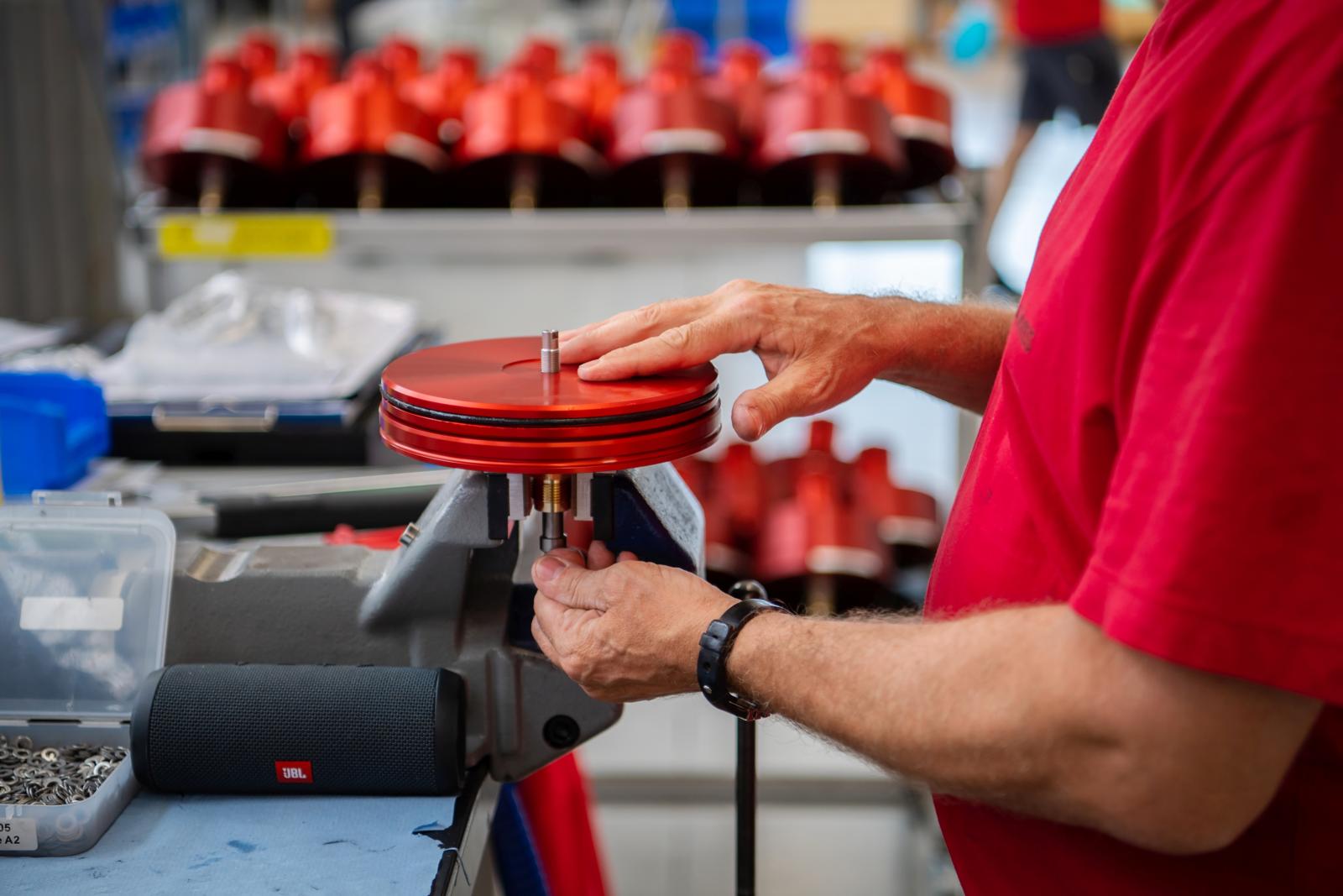 Ein Mann arbeitet an einem scheibenförmigen Bauteil, das in einen Schraubstock eingespannt ist.