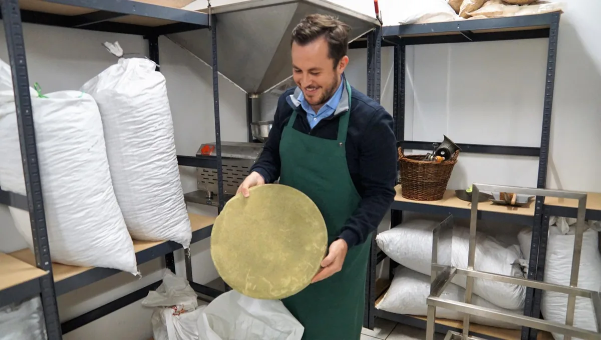 Man sieht Christoph Grammont, der einen Presskuchen in der Hand hält.