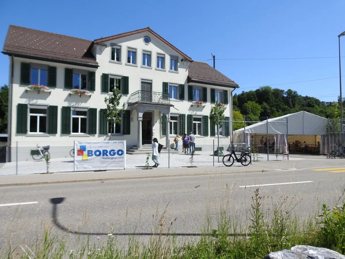 So präsentiert sich das Rikemer Schulhaus heute. Nur die Begrünung am Zaun braucht noch etwas Zeit., Projektleiter und Bauleiter Thomas Wäger führte die Besucher durch das sanierte Schulhaus., Markus Kernen hielt als Präsident der Baukommission eine kurze Ansprache., Ein alter Parkettboden und ein riesiger Touchscreen - auch so kann ein Klassenzimmer aussehen., Markus Kägi als Vertreter der Schulpflege übergibt die Schlüssel an Primarschulpräsidentin Franziska Böni.