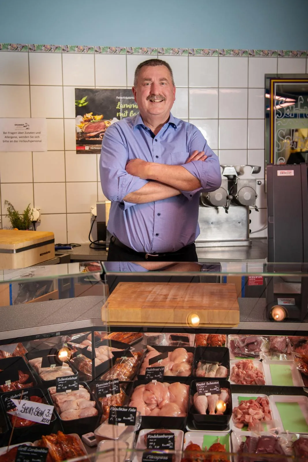 Man sieht Georg Brunner in seiner Metzgerei hinter dem Tresen. 