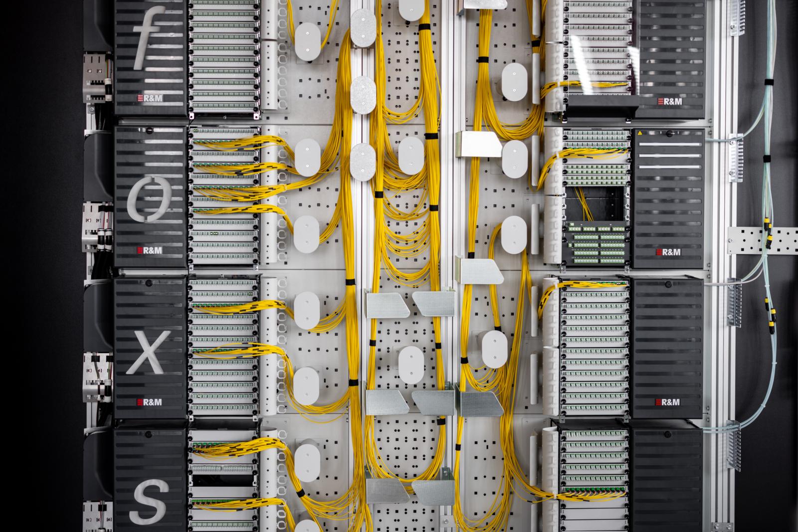 In einem Netzwerkschrank verlaufen vielen gelbe Kabel.
