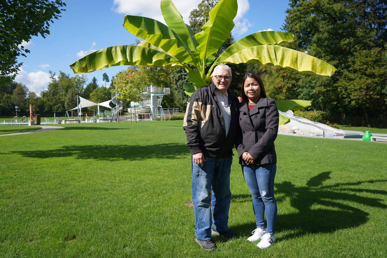 Unter einer Bananenpflanze stehen ein Mann und eine Frau in einer Badanstalt.