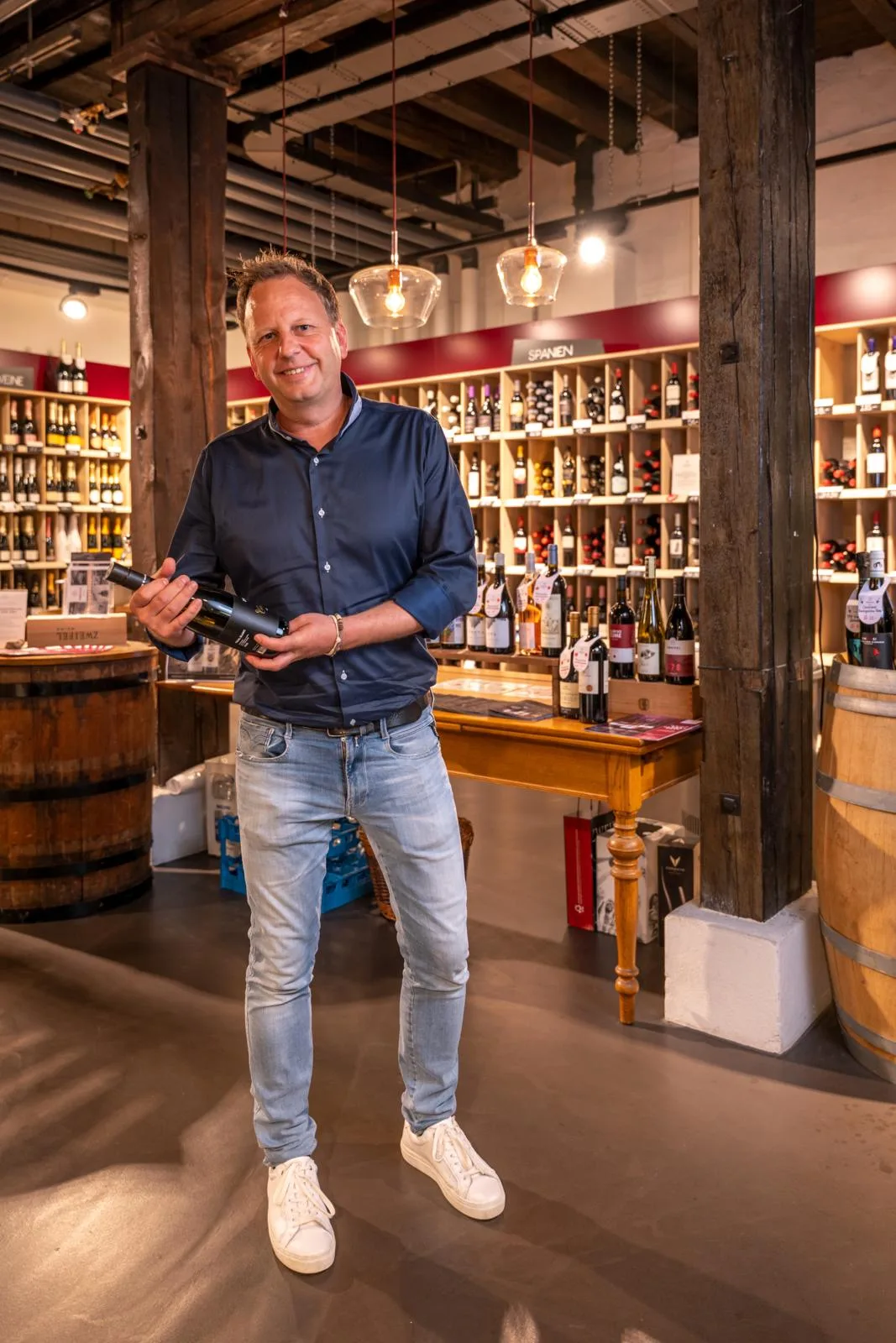 Laut Stefan Zwyssig, CEO von Zweifel Weine & Getränke, bestehen seit Längerem gute Beziehungen zwischen seiner Firma und Girsberger + Sieber. Ein Mann mit Hemd steht in einer Weinhandlung und hält eine Flasche in der Hand.