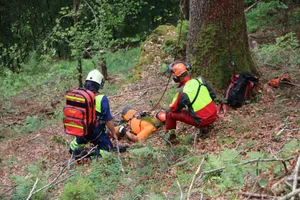 o_img_4377 Ein Angehöriger der Feuerwehr Fischenthal (links) ist zum «verletzten» Forstwart hinuntergestiegen und übernimmt mit einem Kollegen des «Verunglückten» die Erstbetreuung. (Fotos:Ernst Hilfiker), Ein Bild, das die Dimensionen und eines der Hauptprobleme zeigt: Der «Verletzte» im Steilhang ist kaum zu erkennen; der Zugang zu ihm schwierig., Bis die Rettungskrägte eintreffen, wird der «Verletzte» von einem Forstwarkollegen betreut., Erste Angehörige der Feuerwehr Fischenthal sind eingetroffen und seilen sich zur «Unfallstelle» ab., Nun ist auch ein Team des Rettungsdienstes Regio 144 angekommen. Im Vordergrund: eine sogenannte Schleifkorbtrage, in welcher man Verletzte in unwegsamem Gelände bergen kann., Angehörige der Feuerwehr und des Rettungsdienstes heben den «Verletzten» vorsichtig in die Schleifkorbtrage., An Seilen gesichert, tragen die Rettungskräfte den «Verletzten» den Hang hinauf zu einem Wanderweg. , Danach kann der «Patient» zum Rettungswagen getragen und ins Spital gefahren werden.