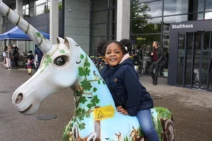 img_1882_0 Die kleine Kenza reitet das Einhorn der Holzkorporation,, Noch Kunst oder schon Werbeplakat?, Das Einhorn der Oberen Mühle., Einhorn mit schnittigem Renn-Design. Man beachte den Stossdämpfer., Wie die meisten anderen ist auch dieses Einhorn nicht gerade in Tarnfarben gehalten., Airbrush-..., --- und Schwamm-Technik., Das Einhorn wird zum Brunnen., Wer hat das hier gemacht? Logisch, der Samariterverein., Glattwerk-Einhorn mit Leni-Riefenstahl-Pose., Einhorn im Smarties-Look. Schmeckt aber nach nichts (der Fotograf hats ausprobiert)., Dieses hier steht vor dem ReZ und hat mit Abstand die schönsten Augen, seufz., Das steht schon lange hier: Einhorn-Plastik auf dem Lindenplatz., Dieses Einhorn hat eine eigene Dusche, und glänzt einfach wunderschön., Auch eine Variante: Einhorn mit Rollen., Keine Überraschung. Blumen-Einhorn vor Blumenladen., Das hier haben die Mitarbeiter der ZKB gemacht., Und das hier haben nicht die Mitarbeiter der UBS gemacht, sondern Kindergärtler., Interaktives Einhorn mit QR-Code auf dem Rücken. Ist das schon Tierquälerei?, Lustig, das Einhorn der Stadtpolizei ist hinter Gitter., Das einzige Einhorn, das bei dem Sauwetter nicht friert., Sieht erbärmlich aus: Ein Einhorn, dem Vandalen das Horn – dessen einzige Schwachstelle – abgerissen haben., Das hier ist der Liebling der Kinder., Mal sehen, ob es die Vandalen auch mit dem Super-Einhorn aufnehmen. , Das Werk von Rolf Knie im Stadthaus., Hier wurde es übergeben., Barbara Sturzenegger bei ihrer Dankesrede., Auch Stadtpräsident André Ingold ist feierlich gestimmt., Wer in Dübendorf etwas auf sich hält, lässt sich die Vernissage nicht entgehen., Bildhauer Bruno Eggenberger fordert die Anwesenden auf, die Einhörner zu beschützen., Bis unters Dach gefüllt: das Stadthaus Dübendorf., Sieht schwer aus, ist es aber nicht., Die Einhörner sind aus Kunststoff, der Rost hier ist nur aufgemalt., Das Einhorn des Verschönerungsvereins., Das Trojanische Einhorn ohne Horn., Bitte beachten Sie die kreative Gestaltung des Sockels., Das Aloha-Einhorn mit Pet-Blumen., Das einzige schwarze Einhorn steht vor dem Sozialamt., Das Einhorn mit der besten Platzierung., Die Feuerwehr war auch kreativ, man beachte das Schlauch-Horn., Und hier zum Abschluss das Astro-Horn beim Innovationspark.