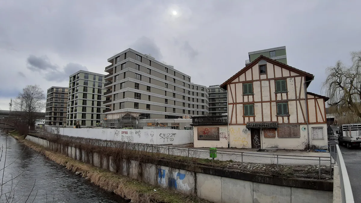 In die Siedlung Riedgarten werden die Mieter ab März einziehen; das alte Kosthaus (rechts) ist seit Jahren unbewohnt. , 215 Wohnungen und hunderte Quadratmeter Büro- und Gewerberäume: Die Siedlung Riedgarten treibt die Urbanisierung weiter voran., Das sogenannte Mittelhaus wurde 1852 erbaut; es diente einst als Unterkunft für junge Arbeiterinnen aus Italien. , Das Unterhaus soll sein äusseres Erscheinungsbild auch nach der Sanierung weitgehend behalten. , In den nächsten Monaten wird um die Häuser eine parkähnliche Grünfläche angelegt.