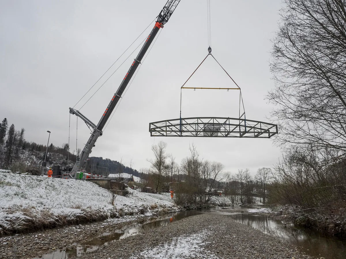 p3300049 Die Hundschilen-Brücke schwebte hoch über der Töss., Von einem Kran aus wurde der Verlad gesteuert., Zu Beginn hob er die Brücke langsam aus ihrer Verankerung., Kurz darauf befand sie sich hoch in der Luft ..., ... und wurde anschliessend vorsichtig auf dem Tieflader platziert., Koordiniert wurde die Arbeit per Funk., Präzision war gefragt., Zentimetergenau wurde die Brücke an ihren Platz bewegt., Schliesslich befand sich die Brücke auf dem Schwertransporter ..., ... und wurde entsprechend gesichert.