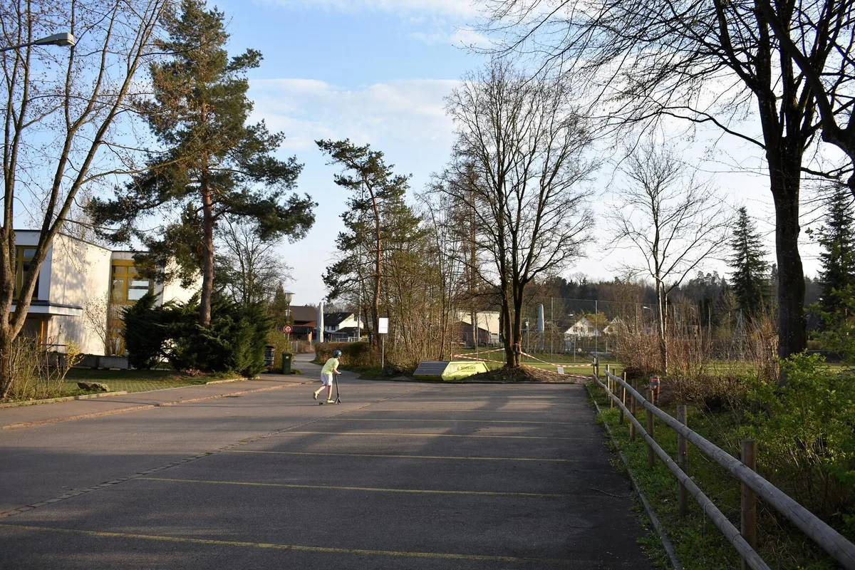 Sind die öffentlichen Plätze gesperrt, wie hier vor der Schulanlage Rietwis, weichen die Kinder auf die Parkplätze aus., Vergangene Woche war der Parkplatz bei der Naturstation Silberweide noch gut besucht. Inzwischen ist der Parkplatz gesperrt, Immer noch beliebt ist der Seeplatz Aaspitz, der ...., ...ausser der gesperrten Grillstelle normal begehbar ist., Der Vorplatz des Mönchhofs ist eigentlich nur noch zum Überqueren gedacht. Kinder überqueren den Platz mit Trottinetts., Einsam hängt ein Kapuzenpulli auf dem gesperrten Skatepark. , Auf dem Schwerzi-Areal sind der Fussballplatz..., ...und die Fitnessgeräte mit Sperrband markiert.