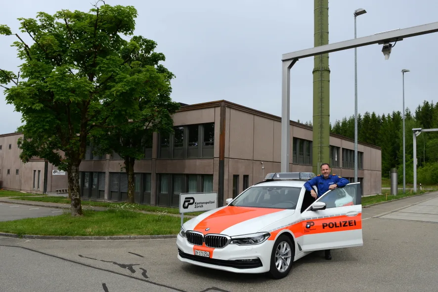 Dienstchef Reto Mülli vor dem sanierten und um einen Stock erweiterten Verkehrspolizeistützpunkt Hinwil., Der Empfangsschalter: Bis hierhin kommt jedermann, danach geht es nur noch mit einem Spezialschlüssel weiter., In der Sicherheitszone zwei befinden sich auch sechs Zellen, sogenannte Abstandsräume., Blick in einen der Abstandsräume., Gearbeitet wird in hellen Büros., Für die immer umfangreichere Ausrüstung stehen mehrere Räume zur Verfügung., Auch ein Ort, an den kein Nicht-Polizist kommt: Der Raum mit den grossen Waffentresoren., , Die Einsatzfahrzeuge können in einer unterirdischen Garage parkiert werden.