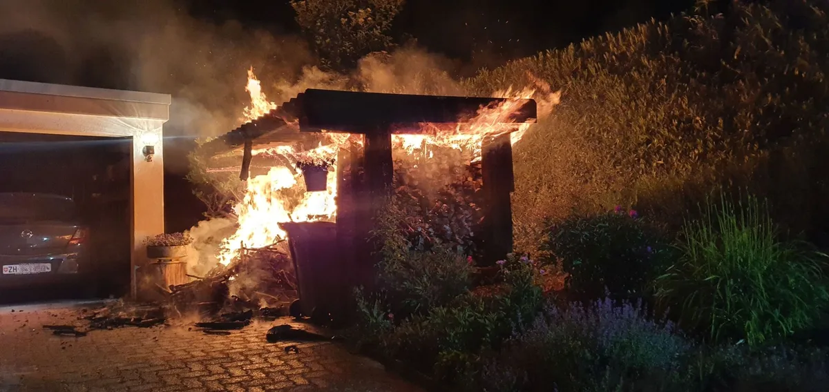 Im Rigiblick geriet ein Unterstand in Flammen, Das Feuer brach wohl gegen 2.30 Uhr aus., Die Feuerwehr konnte den Brand unter Kontrolle bringen., Sie verhinderte zudem ein Überspringen auf die weiteren Gebäude