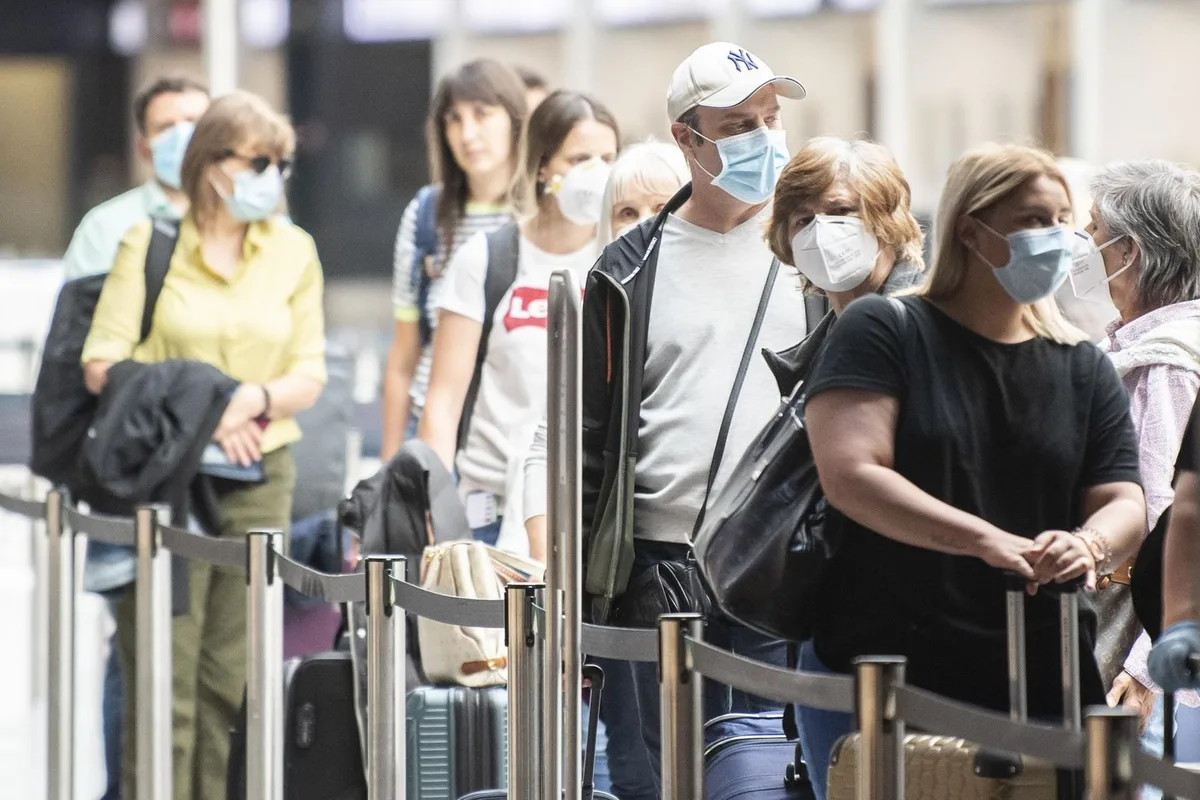 ariqlocdkfpap-mpgbbzwy Die meisten Fluggäste warten auch in Kloten mit Atemschutzmasken vor einem Check-in-Schalter.