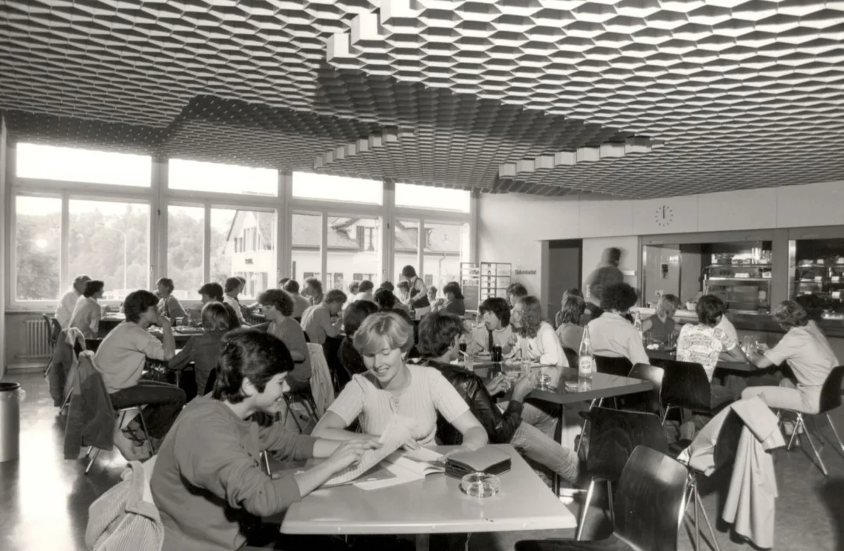 Ein Blick in die Mensa und den Aufenthaltsraum im 1980., So sah der Schreibmaschinenunterricht anno 1987 aus., Die Turnhalle Roosriet wurde ebenfalls 1987 gefeiert., Ein Blick ins Sprachlabor von selbigem Jahr., In den 1980er Jahren fand dieses Konzert statt., Noch viel früher - aber schon zur Zeit mit Frauen an der Schule - lernte man das Maschinenschreiben so.