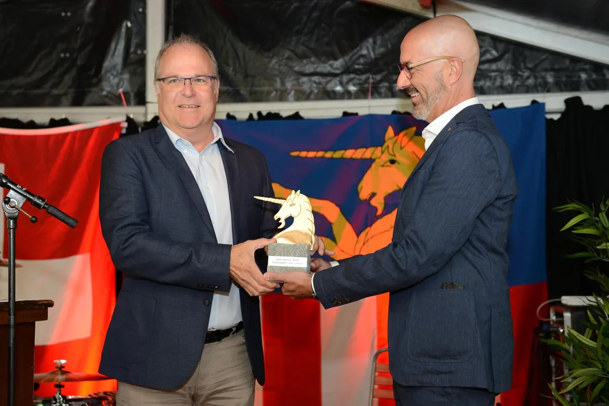 Urs Wüst (links) wird von Stadtpräsident André Ingold geehrt., Stadtpräsident Ingold während seiner Laudatio., Den Dübi Award in der Kategorie Sport erhielt der Curler Yves Wagenseil., Wurden für ihr Hilfsangebot während der Corona-Pandemie ausgezeichnet: Urs und Melanie Oettlin (links) sowie Franziska Wick., Chantal Galladé hielt die Ansprache an der offiziellen Dübendorfer Bundesfeier., Galladé war Nationalrätin und ist heute die Präsidentin der Kreisschulpflege Winterthur Stadt-Töss., Musikalische Unterhaltung..., ... gehörte mit zum Programm., Rund 100 Personen nahmen an der Feier vor der Oberen Mühle teil – hier wars gerade mal kurz trocken.