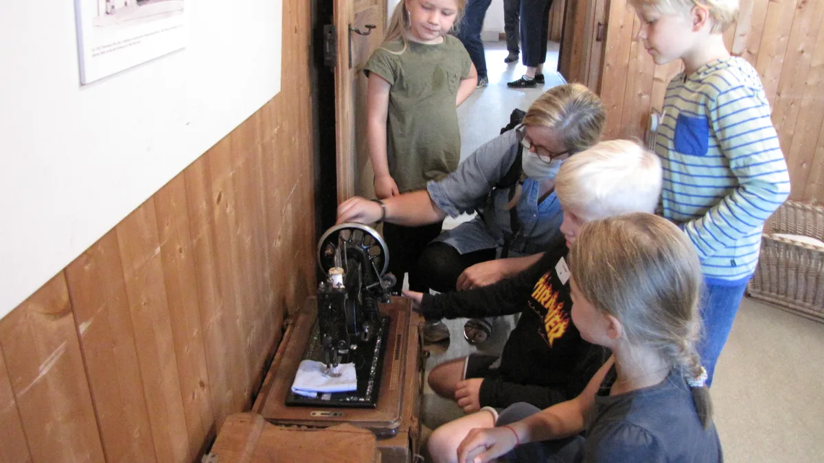 wila-03 Die Neuzuzüger besuchen das Ortsmuseum. Kinder lassen sich eine alte Nähmaschine erklären., In der Kirche Wila gibt es freigelegte Fresken zu entdecken., Marianne Heusi und Isabel Stuhlmann zeigen die Baugeschichte der Kirche Wila., In der Windenmacherei gibt es für die Neuzuzüger eine Führung., Hansruedi Schnurrenberger erklärt das Wilemer Wassersystem.