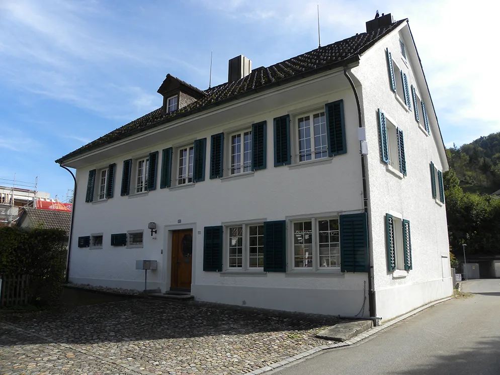 Das heutige Pfarrhaus wirkt gemäss der Denkmalpflege etwas steif., So sah das Pfarrhaus (in der Mitte des Fotos) aus, als es noch beschaulicher war in Turbenthal., Pfarrerin Isabel Stuhlmann sitzt im Arbeitszimmer mit der uralten Holzdecke., Blick auf den alten Dorfkern bei der Sandplatte: Vorne auf dem Foto steht das Pfarrhaus umgeben von Garten.