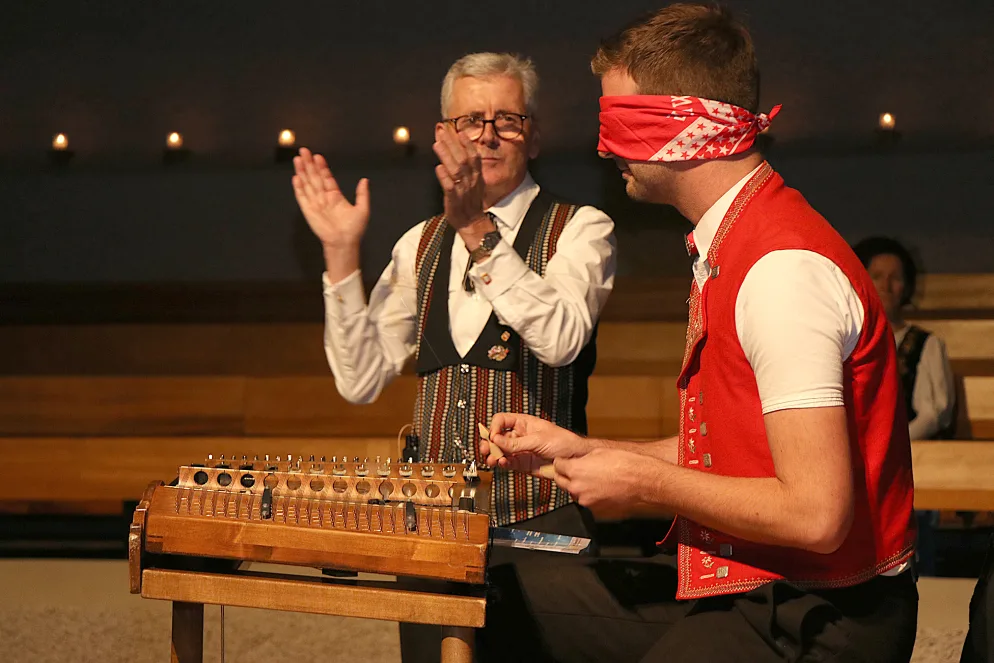 klein_adventskonzert_jodelclub_duebendorf_blindes_hackbrett_0 Er trifft die Saiten auch mit verbundenen Augen: Nicolas Senn beweist sein Können am Hackbrett., Der Chor inklusive Verstärkung in der reformierten Kirche Wil., Die Stargäste Lisa Stoll und Nicolas Senn im Einsatz., Lisa Stoll und Nicolas Senn mit Moderator René Zünd., Dirigent Alex Eugster bekommt Geschenke für einen gemütlichen Ruhestand.