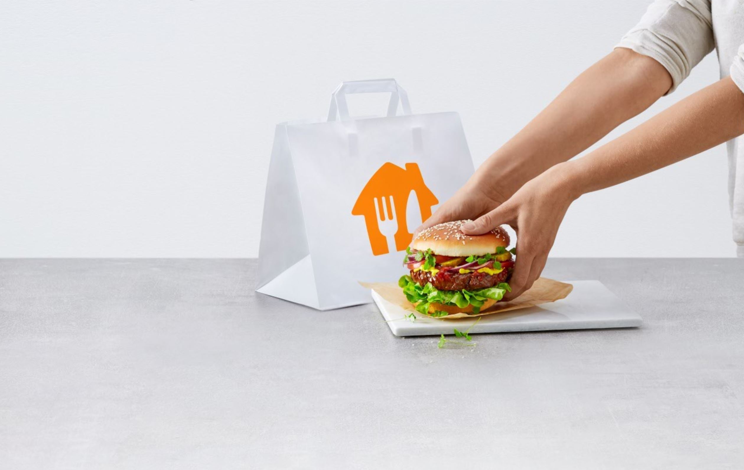 Auf dem Bild greifen zwei Hände nach einem Hamburger. 