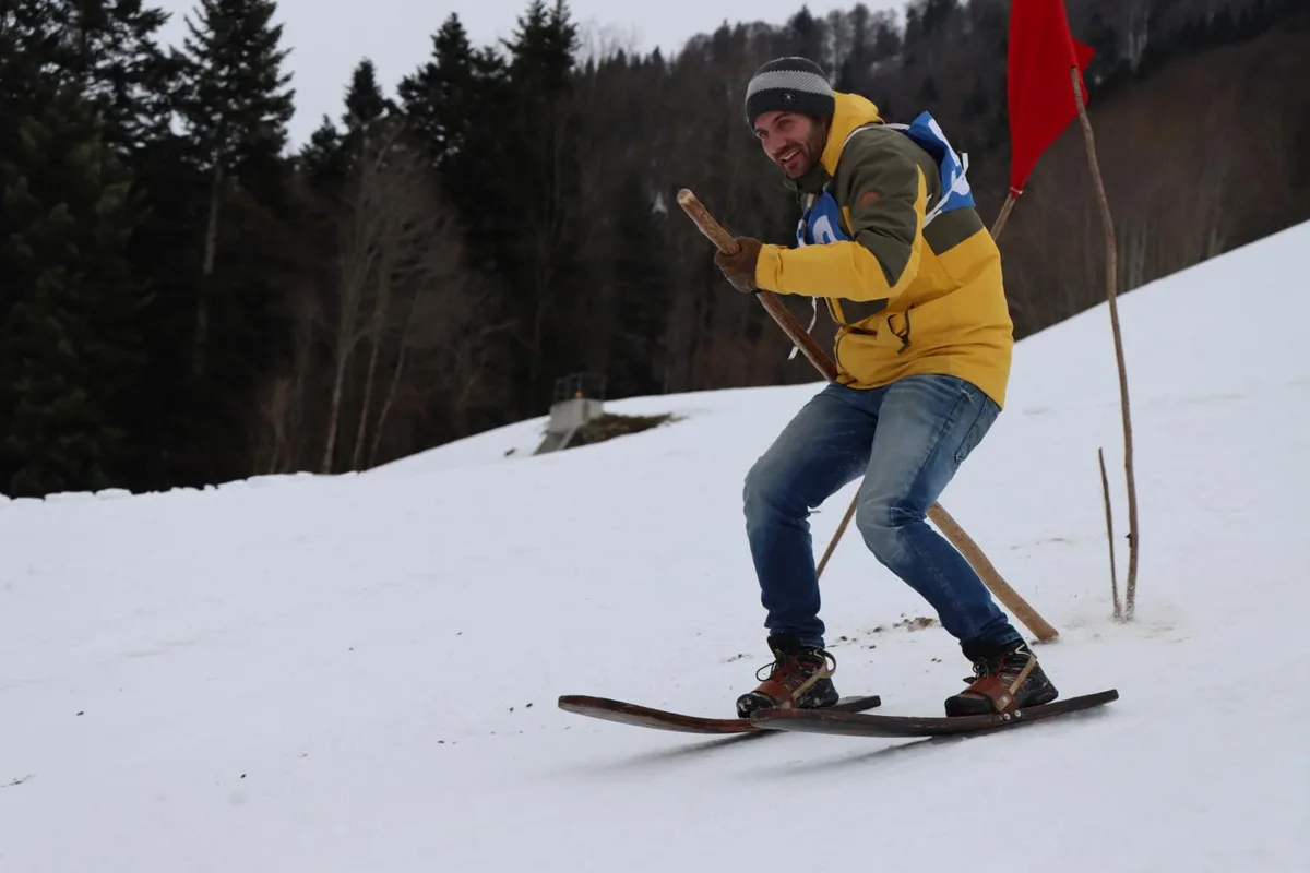 Es geht beim Fassdaubenfahren vor allem um die Balance, denn die Bretter haben keine Kanten – wie herkömmliche Ski., Das Fahren ist dabei keine Frage des Alters. Viel mehr geht es darum, den richtigen mix aus Sicherheit und Tempo zu finden., Eigene Fassdauben dürfen nicht benutzt werden. Es gilt, ein Paar aus dem Materialdepot des organisierenden Vereins zu beziehen., Ins Ziel gestürzt? Egal, die Leute hier wollen miteinander vor allem auch ein Fest erleben.
