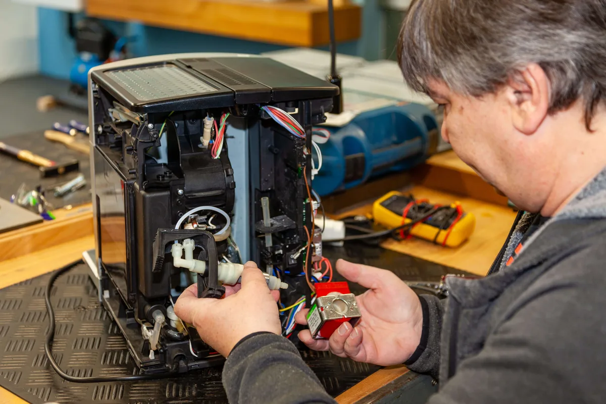 Ein freiwilliger Mitarbeiter repariert eine Kaffeemaschine im Repair Café Tösstal in Turbenthal. 