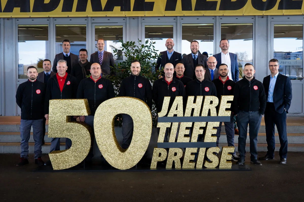 Das Team als Schlüssel zum Erfolg: 20 autobegeisterte Mitarbeitende kümmern sich täglich um die Kunden. (Foto: Paulo Pereira) Die Mitarbeitenden von Auto Discount Uster stehen hinter dem Jubiläumsschild mit der Aufschrift «50 Jahre tiefe Preise».