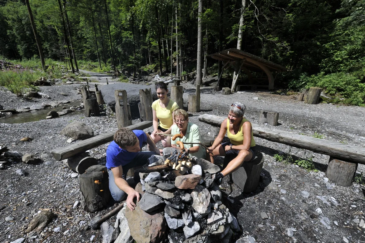 Bräteln mit Komfort: Entlang der Wanderroute laden gut ausgestattete Grillplätze immer wieder zum Verweilen ein. Eine Personengruppe grilliert an einer Feuerstelle in der Aaschlucht bei Engelberg.