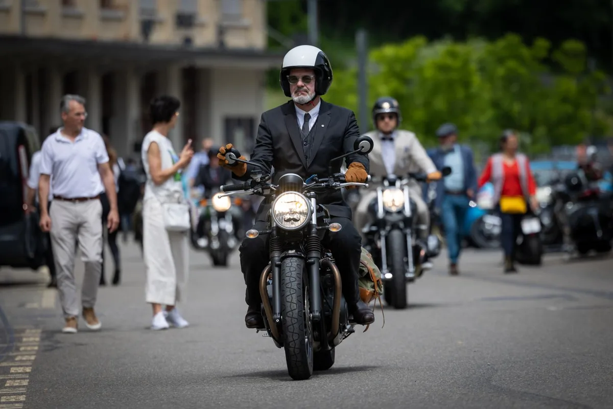 Ein Motorradfahrer mit einem schwarz-weissen Helm. Im Hintergrund mehrere andere Fahrer.