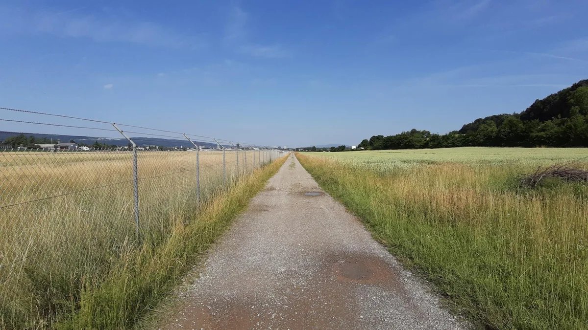 Wanderweg zwischen Stacheldraht und Feldern. 
