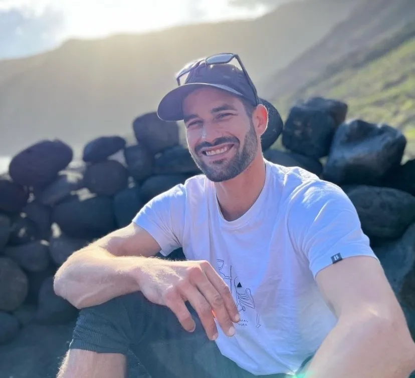 Mann mit Cap und grauem T-Shirt schaut in Richtung des Fotografen.