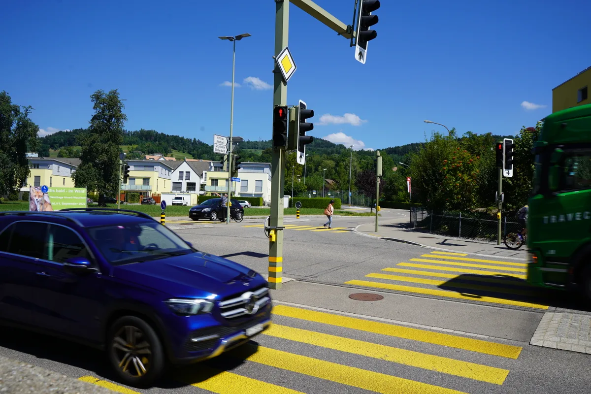 Kreuzung mit Ampel, Fussgängerstreifen und Autos. 