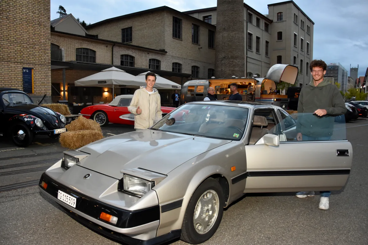 goodwoodbynightoldtimer_kemptthal_robinmoehllinkscrispinwaltenspuelrechts_1_mav Robin Möhl (links) und Crispin Waltenspül kamen aus der Ostschweiz nach Kemptthal mit ihrem Gefährt., Auf einer Leinwand konnten lange vergangene Rennen geschaut werden.