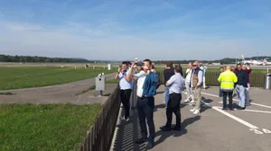 ausflug_2022_gemeinderat_duebendorf_5_preview Bei Pistenkreuz durften die Fahrgäste für ein paar Minuten aussteigen. , Mit dem Car fuhren die Dübendorfer zum Flughafen. , So geht Lokalpatriotismus: Cornelia Schwarz und ihr Mann Blacky lotsen die Reisegruppe mit Dübi-Fähnchen durch das Areal., Die Landung eines A380 aus unmittelbarer Nähe war einer der Höhepunkte der Rundfahrt. , Die Geräuschkulisse direkt neben einem startenden Flieger war beeindruckend. , Cornelia Schwarz' Kurzansprache beim Apéro Nummer 1. , Einer der drei Rega-Jets im Hangar: Wegen Wartungsarbeiten durften die Besucher das Flugzeug nicht betreten. , Das ausgebaute Triebwerk eine Rettungshelis wird gewartet., Beim Besuch in der Rega-Einsatzzentrale konnten die Anwesenden verfolgen, wo die Rega gerade einen Einsatz fliegt. , Apéro Nummer 2 im Restaurant Alter Tobelhof. , Gruppenfoto in Gockhausen.