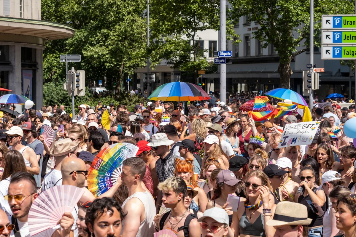 Pride Zürich. Viele Menschen stehen in der Sonne und tanzen.