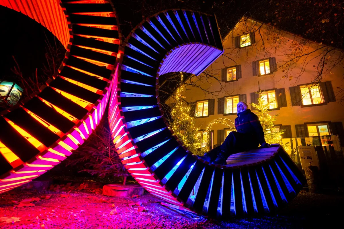 winterzauber-oberemuehle-duebendorf-crm-16_preview Die Umgebung der Oberen Mühle ist in buntes Licht getaucht. , Am Wochenende wurden die «Lichtertraumwelten» mit einem Freiluftspektakel eröffnet. , Zu Gast war der Lichtkünstler Christian Ziegler., Anders als jeweils an der Dübendorfer Dreikönigsfeier bestand diesmal aber keine Verbrennungsgefahr..., ... denn anstelle von Feuer setzte er auf kaltes Licht. , Etwas Feuer gab es aber dennoch., So konnten sich die Besucherinnen und Besucher..., ... an den knisternden Flammen wärmen., Die Exponate auf dem Gelände wurden von Künstschaffenden mit und ohne Behinderungen gestaltet.