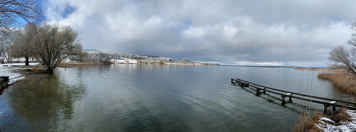 Blick auf den Greifensee und eine Schneelandschaft in der Ferne.