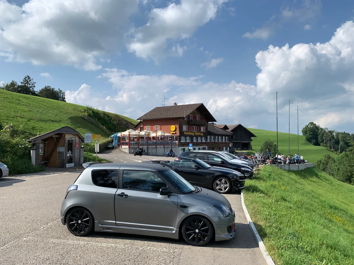 Autos und Motorräder stehen vor dem Gasthaus Hulftegg.