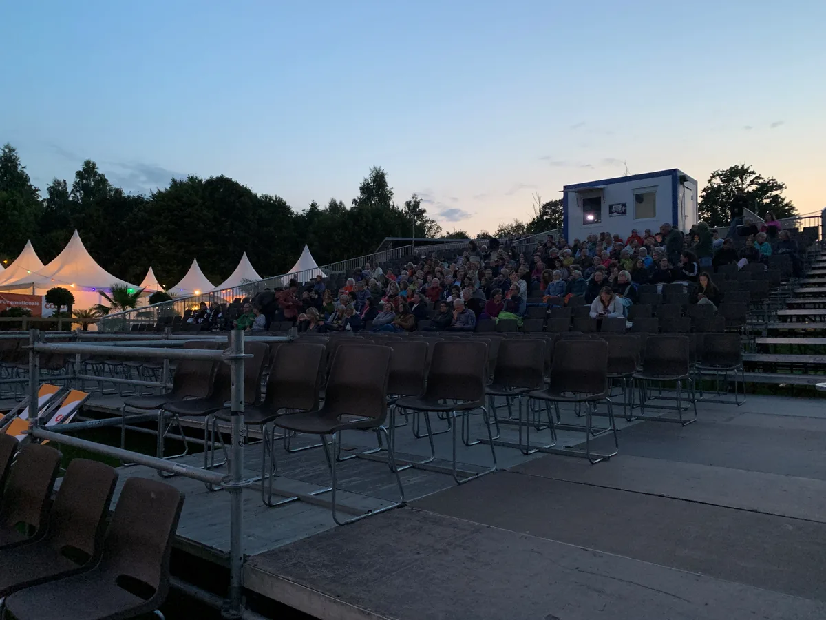 Leute sitzen auf der Tribüne des Kino-Open-Airs in Uster.