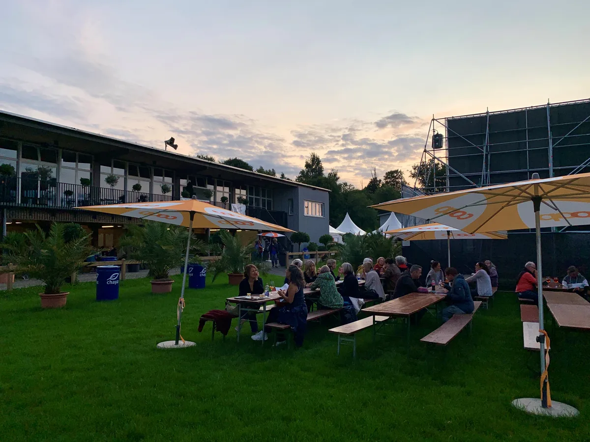 Leute sitzen an Festbänken hinter der Kinoleinwand im Buchholz Uster.