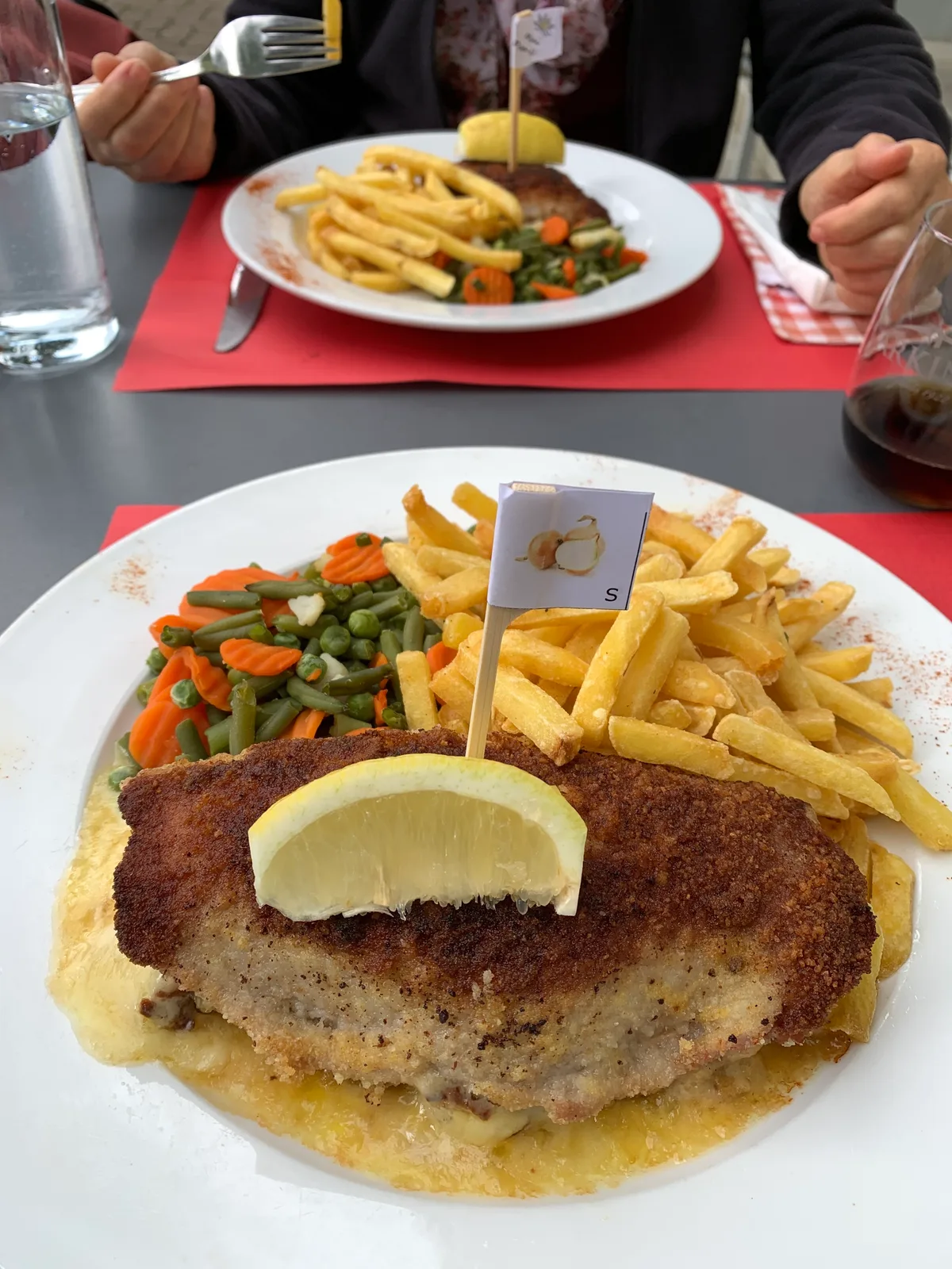 Blick auf zwei Teller mit Cordon bleu, Pommes frites und Gemüse. 